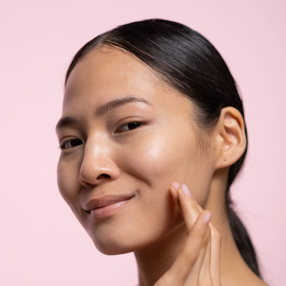 Woman with glowing glass skin applying skincare